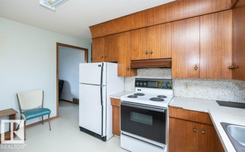 Kitchen featuring wood cabinetry, solid surface countertops, white tile backsplash, and an electric range - 2021 Twp Rd 604, Rural Westlock County, AB 