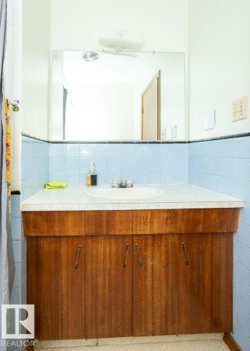 Bathroom vanity with a white countertop and integrated sink, wood-finish cabinetry, and a full-width mirror - 2021 Twp Rd 604, Rural Westlock County, AB 