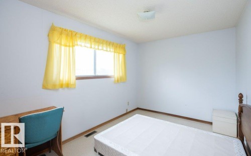 Bedroom with light-colored walls, carpeted flooring, and a single window featuring yellow valance and curtains - 2021 Twp Rd 604, Rural Westlock County, AB 