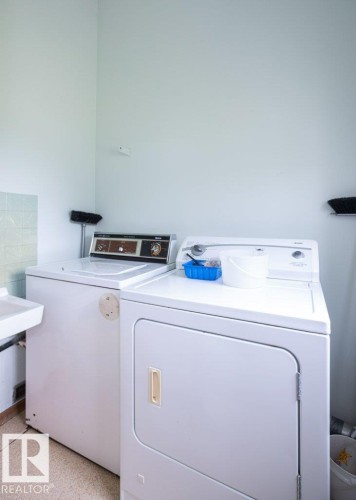 Dedicated laundry area featuring a built-in utility sink and light-toned wall paneling - 2021 Twp Rd 604, Rural Westlock County, AB 
