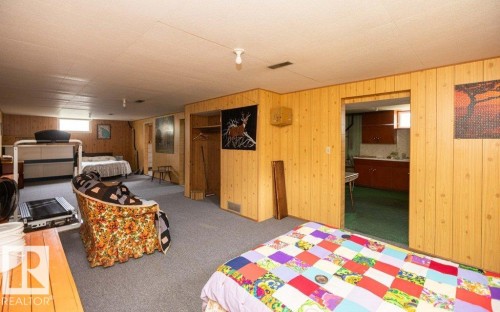 Lower level space featuring wood-finish wall paneling, gray carpet flooring, and an exposed ceiling beam - 2021 Twp Rd 604, Rural Westlock County, AB 