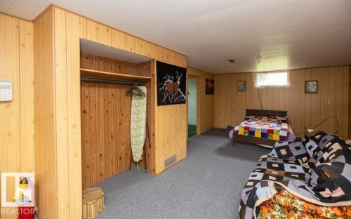 Spacious room with wood-finish paneling, grey carpeting, and a built-in closet with shelving and a clothes rod - 2021 Twp Rd 604, Rural Westlock County, AB 