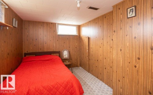 Room featuring wood-paneled walls, a small horizontal window, and patterned carpet flooring - 2021 Twp Rd 604, Rural Westlock County, AB 
