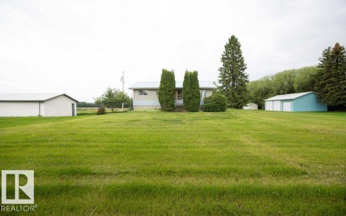 Expansive green lawn surrounding a light-colored residence with multiple outbuildings - 2021 Twp Rd 604, Rural Westlock County, AB 