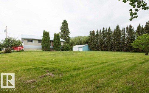 Expansive green lawn with a residential structure featuring light-colored siding and a metal roof - 2021 Twp Rd 604, Rural Westlock County, AB 