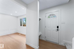 Entryway featuring a paneled door with an arched transom, a built-in shelf, and wood-finish flooring - 