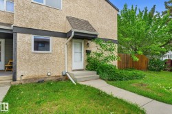 Stucco exterior with dark trim accents, featuring a paved walkway leading to the front entry - 