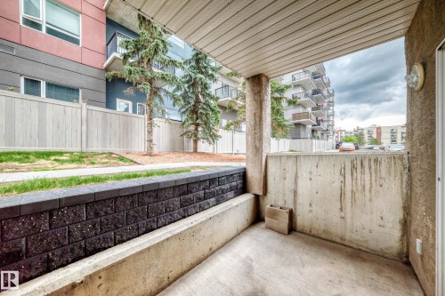 Outdoor patio area featuring concrete flooring and a partial concrete wall - 126 10535 122 Street, Edmonton, AB 