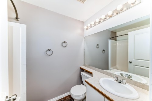 Bathroom featuring a single vanity with an integrated sink, a large wall-mounted mirror, and overhead strip lighting - 126 10535 122 Street, Edmonton, AB 