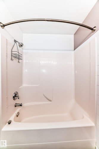 White fiberglass tub and shower combination with chrome fixtures and a curved shower rod - 126 10535 122 Street, Edmonton, AB 