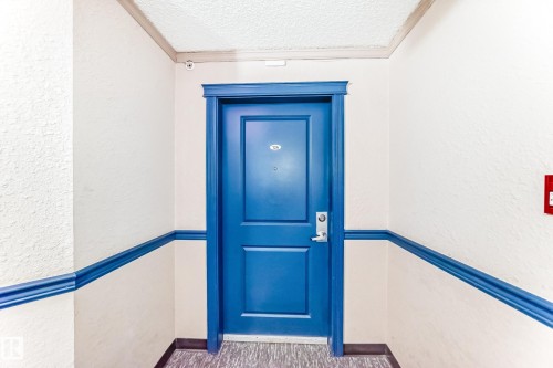 Suite Entryway featuring a blue paneled door with door number, textured walls, and wood-finish flooring - 126 10535 122 Street, Edmonton, AB 