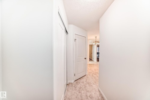 Entryway featuring light-toned flooring, white walls, and a sliding closet door - 126 10535 122 Street, Edmonton, AB 