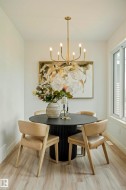 Dining area with light wood-finish flooring, white baseboards, and a large window - 