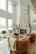 Two-story living area featuring a full-height stone fireplace with a wood mantel - 