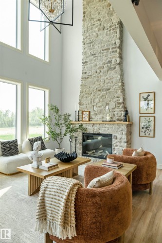Two-story great room featuring a full-height stone-clad fireplace with a wood mantel - 3329 Chickadee Drive, Edmonton, AB 