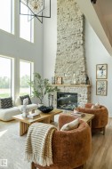 Two-story great room featuring a full-height stone-clad fireplace with a wood mantel - 