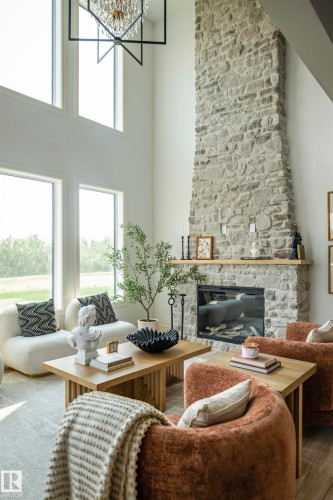 Great room featuring a floor-to-ceiling stone fireplace with an integrated linear firebox and a natural wood mantel - 3329 Chickadee Drive, Edmonton, AB 