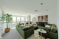 Spacious open loft area featuring a wrought iron railing, expansive windows, recessed lighting, and a modern chandelier - 