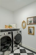 Laundry area featuring striking black and white checkered floor tiling, a convenient built-in shelf, and crisp white baseboards - 