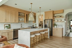 Central kitchen island with waterfall countertop, complemented by light wood-finish cabinetry - 