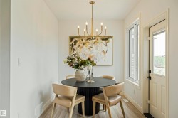 Dining area featuring a contemporary chandelier, light wood-finish flooring, and a glass-paneled exterior door - 