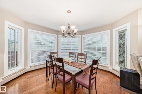 Dining area featuring wood-finish flooring, a contemporary chandelier, and a bay of multiple windows - 512 3 Perron Street, St. Albert, AB 