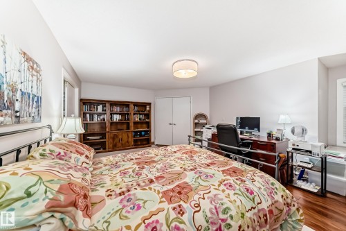 Spacious room featuring wood-finish flooring, a built-in wood bookcase, and a ceiling-mounted drum light fixture - 512 3 Perron Street, St. Albert, AB 