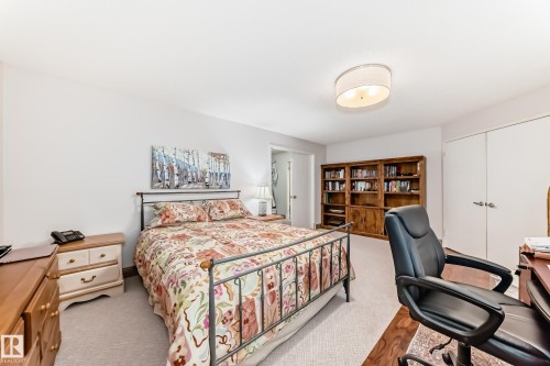 Bedroom featuring a metal bed frame, light-toned carpeting, and a built-in wood bookcase - 512 3 Perron Street, St. Albert, AB 