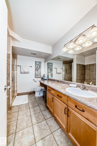 Spacious bathroom featuring an extended vanity with dual sinks, warm wood-finish cabinetry, and a large mirror - 512 3 Perron Street, St. Albert, AB 