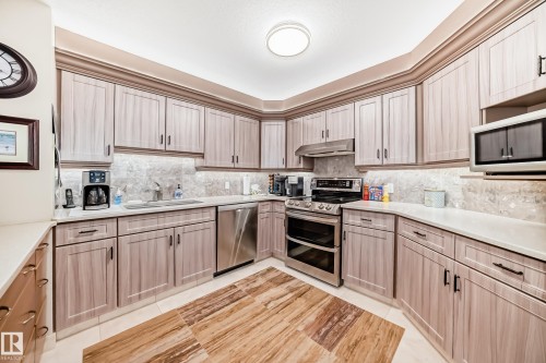 U-shaped kitchen featuring light wood-finish cabinetry, white countertops, and a stone-patterned backsplash - 512 3 Perron Street, St. Albert, AB 