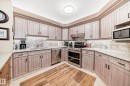 U-shaped kitchen featuring light wood-finish cabinetry, white countertops, and a stone-patterned backsplash - 512 3 Perron Street, St. Albert, AB 