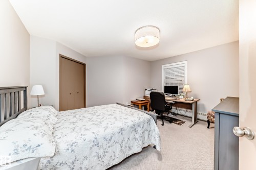 Bedroom featuring light gray walls, plush carpeting, a window with horizontal blinds, a ceiling-mounted drum light fixture, and a built-in closet with bi-fold doors - 512 3 Perron Street, St. Albert, AB 