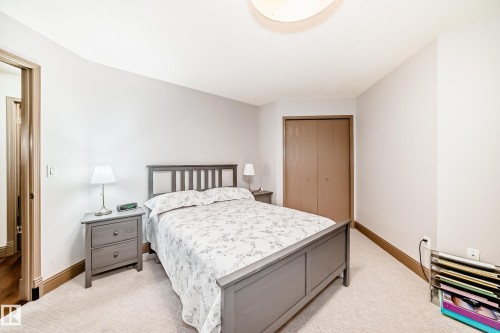 Carpeted room featuring a ceiling-mounted light fixture, light-colored walls, wood-finish trim, and a bi-fold closet door - 512 3 Perron Street, St. Albert, AB 