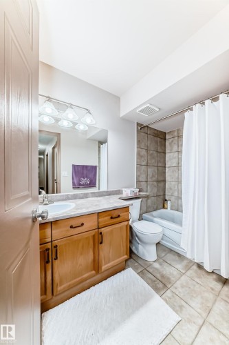 Full bathroom featuring a single vanity with wood-finish cabinetry, a light-toned countertop, and an integrated basin - 512 3 Perron Street, St. Albert, AB 