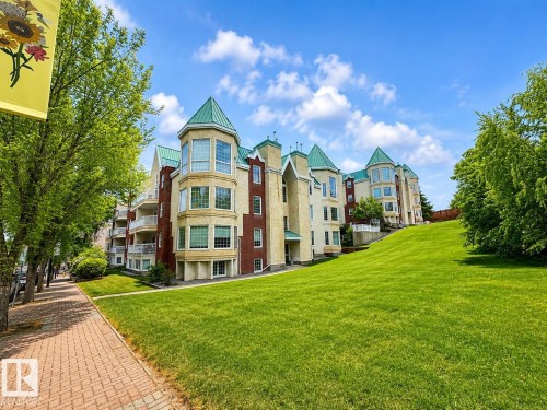Multi-story residential building featuring brick and stucco facade with bay window elements, green peaked roofs, and private balconies - 512 3 Perron Street, St. Albert, AB 