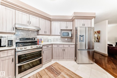 Corner kitchen featuring light wood-finish cabinetry, stainless steel appliances, a tile backsplash, and light countertops - 512 3 Perron Street, St. Albert, AB 