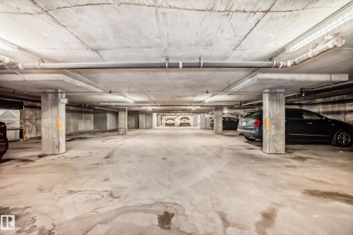 Underground parking garage featuring concrete pillars, exposed ceiling pipes, and fluorescent lighting - 512 3 Perron Street, St. Albert, AB 