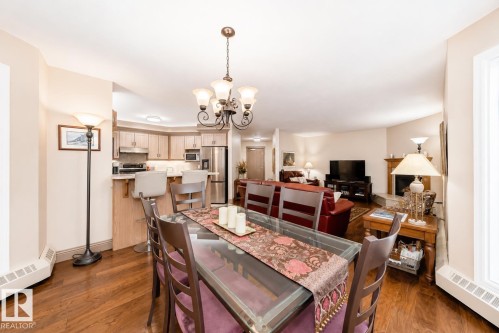 Dining area featuring a glass-top table, a decorative chandelier, and wood-finish flooring - 512 3 Perron Street, St. Albert, AB 