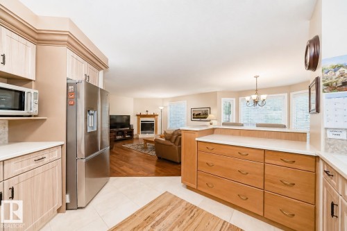 Open-concept kitchen featuring light wood-finish cabinetry, a stainless steel refrigerator, and light countertops - 512 3 Perron Street, St. Albert, AB 
