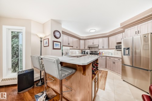 Kitchen featuring light wood-finish cabinetry, stainless steel appliances, and a central island with a solid surface countertop - 512 3 Perron Street, St. Albert, AB 