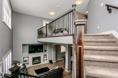 Two-story interior featuring a carpeted staircase with a dark wood newel post and wrought iron spindles - 21807 97 Avenue, Edmonton, AB 