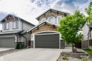 Two-story residence featuring a dark gray garage door, stone accents, shingle siding, and a concrete driveway - 21807 97 Avenue, Edmonton, AB 