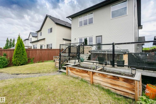 Spacious backyard featuring a raised garden bed, a multi-level deck with black railings, and a privacy fence - 21807 97 Avenue, Edmonton, AB 