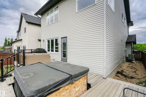 Rear exterior featuring light-colored siding, a multi-level wood deck, and a single glass-paneled door - 21807 97 Avenue, Edmonton, AB 