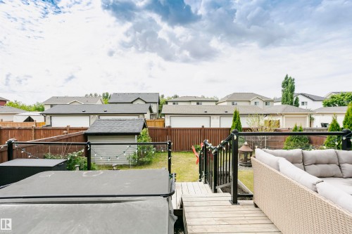 Wood-finish elevated deck featuring black metal railings with glass inserts - 21807 97 Avenue, Edmonton, AB 