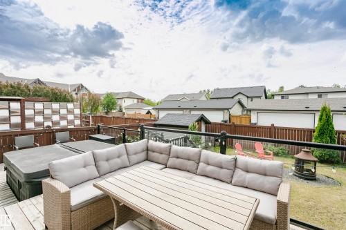 Expansive outdoor deck featuring wood flooring and a glass panel railing - 21807 97 Avenue, Edmonton, AB 