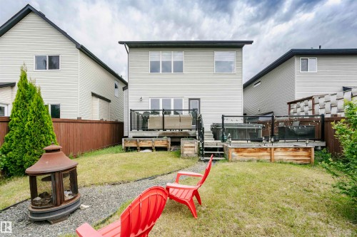 Expansive backyard featuring a multi-level deck with glass panel railings, a raised garden bed, and a gravel pathway - 21807 97 Avenue, Edmonton, AB 
