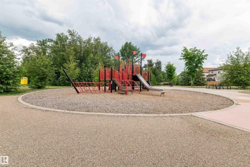 Community playground featuring a multi-level structure with slides, a climbing net, and ample open space - 21807 97 Avenue, Edmonton, AB 