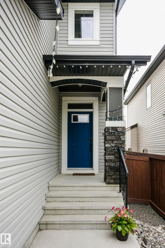 Entryway featuring a bold blue front door, concrete steps, and a sheltered porch with black trim - 21807 97 Avenue, Edmonton, AB 