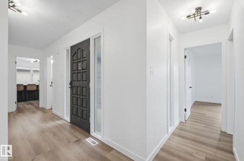 Corridor with a textured ceiling and light wood-style floors - 2722 104A Street, Edmonton, AB 